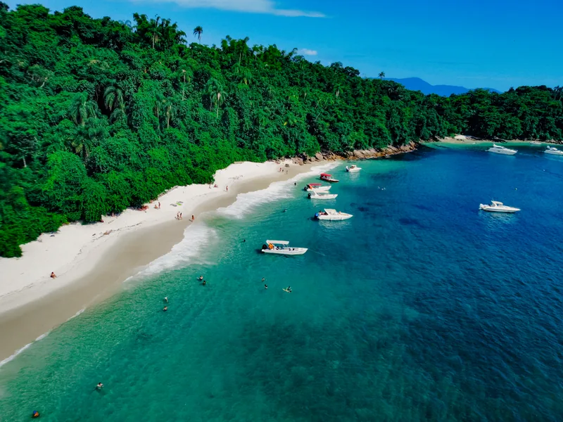 Praia de águas calmas com barcos ancorados